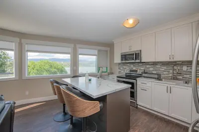 a kitchen with white cabinets and a table with chairs at Lakeviews, big yard/deck, minutes to Silver Star/Golf/Wineries. in Vernon