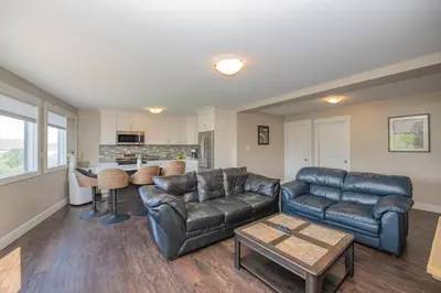 a living room with two leather couches and a table at Lakeviews, big yard/deck, minutes to Silver Star/Golf/Wineries. in Vernon
