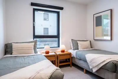 two beds in a room with a window at Escape to Revy - Beautifully Designed Condo in Revelstoke