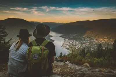 a man and woman sitting on top of a mountain overlooking a valley at Dancing Bear Inn in Nelson
