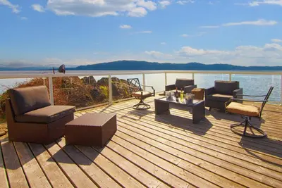 a wooden deck with chairs and a table on the water at Exclusive Private Island - Pacific Ocean Paradise in Madeira Park