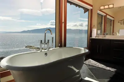 a bath tub in a bathroom with a view of the water at Exclusive Private Island - Pacific Ocean Paradise in Madeira Park