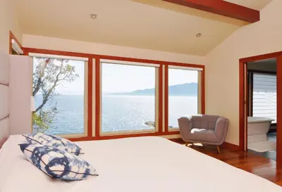 a bedroom with a bed and a view of the ocean at Exclusive Private Island - Pacific Ocean Paradise in Madeira Park