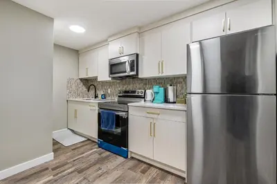a kitchen with white cabinets and a stainless steel refrigerator at Newly renovated 2 bedroom basement suite in Calgary