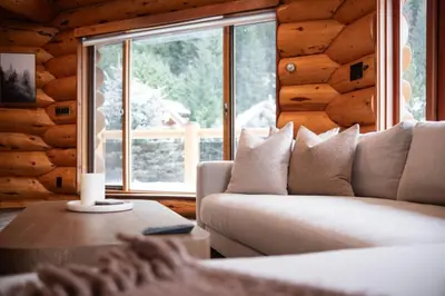 a living room with a couch and a large window at Snowridge Chalet by Outpost Whistler in Whistler