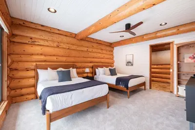 two beds in a room with wooden walls at Snowridge Chalet by Outpost Whistler in Whistler