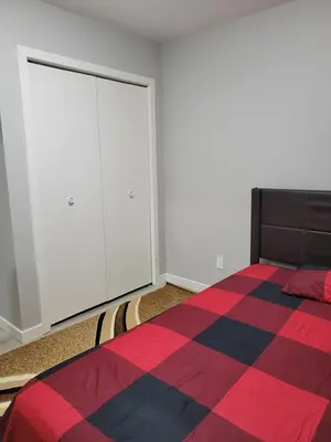 a bedroom with a bed and white cabinets at Brand New 2 Bedroom Basement Suite with Wifi in Edmonton