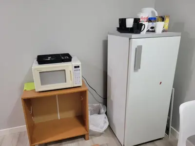 a microwave on a table next to a refrigerator at Brand New 2 Bedroom Basement Suite with Wifi in Edmonton