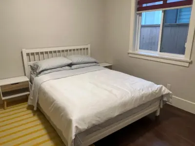 a white bed in a bedroom with a window at Cozy and Private Suite in Richmond in Richmond