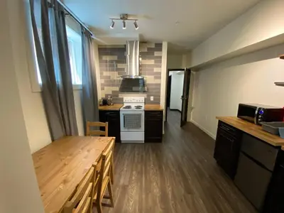 a kitchen with a table and a stove top oven at Dt 1Bed 1bath Cozy Suite 8 Min Walk To Arena in Edmonton