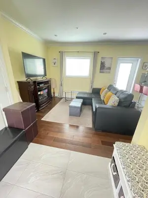 a living room with a black couch and a tv at Arbutus summer house in Vancouver