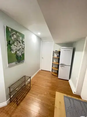 an empty living room with a refrigerator and wooden floors at Arbutus violet room in Vancouver