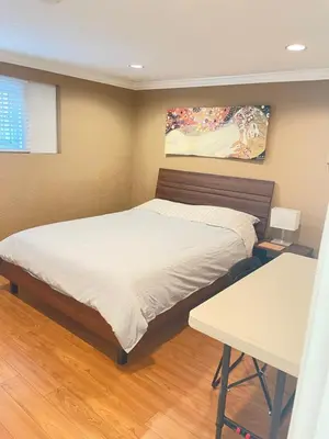 a bedroom with a bed and a table and a painting at Arbutus Jasmine room in Vancouver
