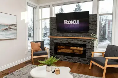 a living room with a tv on a brick fireplace at The Azure, Near DT & University, TWO King Beds! in Edmonton