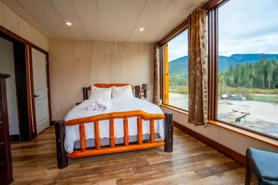a bedroom with a bed and a large window at River Safari Lodge in Blue River