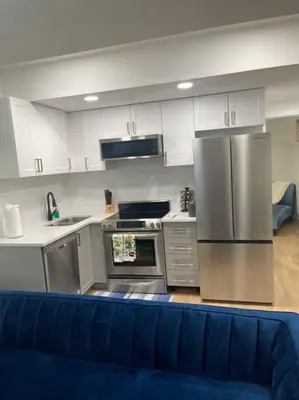 a kitchen with stainless steel appliances and a blue couch at Modern 2Bedroom suite in SW Edmonton close to Edmonton International Airport in Edmonton