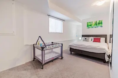 a white bedroom with a bed and a window at Walkout Basement Suite, 2 BDR 4BD, Bright and Spacious in Calgary