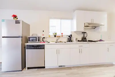 a kitchen with white cabinets and a refrigerator at Walkout Basement Suite, 2 BDR 4BD, Bright and Spacious in Calgary