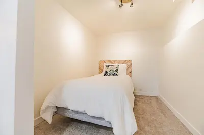a bedroom with white walls and a bed with a pillow at Walkout Basement Suite, 2 BDR 4BD, Bright and Spacious in Calgary