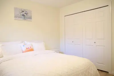 a bedroom with a white bed and a white closet at A private suite in Port Moody in Port Moody