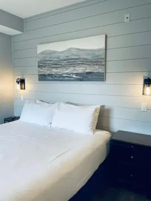 a bedroom with a white bed with a painting on the wall at Family friendly 2BR/2BA condo - Views & Location!! in Canmore