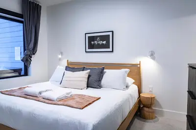 a bedroom with a bed with white sheets and pillows at Tumbledown Condo by Revelstoke Vacations in Revelstoke