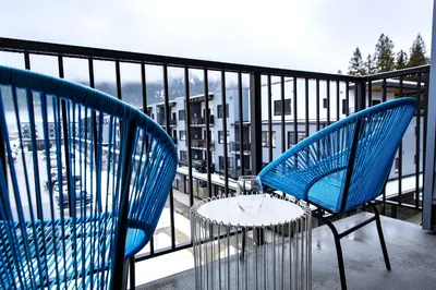 two blue chairs and a table on a balcony at Tumbledown Condo by Revelstoke Vacations in Revelstoke