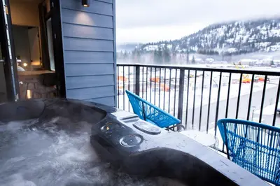a hot tub on a balcony with two chairs at Tumbledown Condo by Revelstoke Vacations in Revelstoke