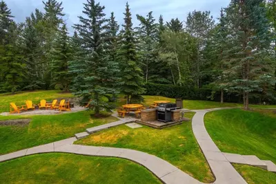 a backyard with a grill and a table and chairs at B211 MTN View ground floor town house- 2BD, Sleeps 8, hot tub, free parking, close to Banff in Canmore