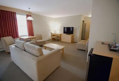a living room with a white couch and a tv at Eldorado, a Coast Hotel in Dawson City