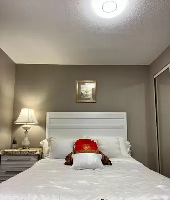 a bedroom with a white bed with a red pillow at West Edmonton Perle Palace in Edmonton