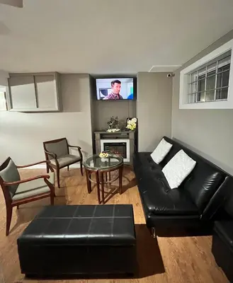 a living room with a black leather couch and a tv at West Edmonton Perle Palace in Edmonton