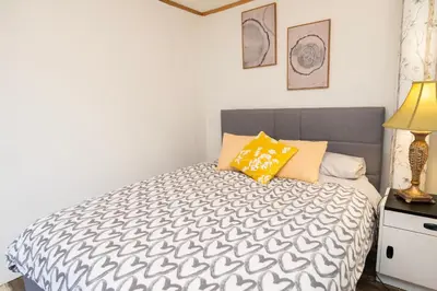 a bedroom with a bed with a gray and white comforter at 3 Bedroom Gardenside Downtown Home in Whitehorse