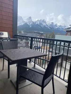a table and chairs on a balcony with mountains at Sweet Condo Canmore GR\uff1a\uff09 in Canmore
