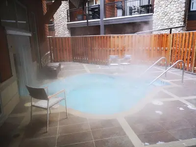 a swimming pool with a chair and a table at Sweet Condo Canmore GR\uff1a\uff09 in Canmore