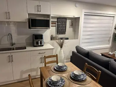 a kitchen and living room with a table and a couch at New, Spacious 2 Bedrooms in Downtown With Free Parking! in Maple Ridge District Municipality
