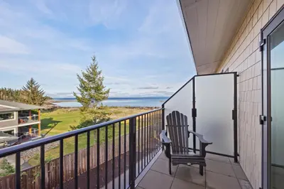 a balcony with a chair and a view of the ocean at Ocean's 7 at THE BEACH HOUSE in Campbell River