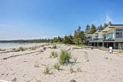 a beach in front of a house with a building at Ocean's 7 at THE BEACH HOUSE in Campbell River