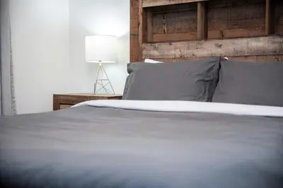 a bed with gray pillows and a table with a lamp at Revelstoke Marvel - Two Bedroom with Hot Tub in Revelstoke