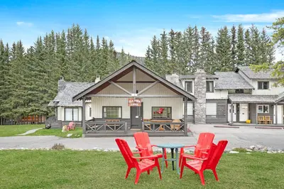 a group of red chairs and a table in front of a house at Elkhorn Lodge Vacation Rentals in Banff