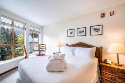 a bedroom with a bed with a backpack on it at Cascade by Elevate Vacations in Whistler