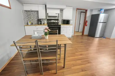 a kitchen with a wooden table with chairs and a refrigerator at Cozy 2-Bedroom Basement Suite Retreat Calgary in Calgary