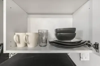 a shelf with plates and cups and a glass at Cozy 2-Bedroom Basement Suite Retreat Calgary in Calgary