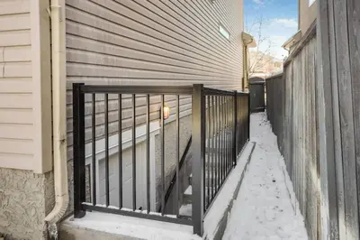 a metal gate on the side of a house in the snow at Cozy 2-Bedroom Basement Suite Retreat Calgary in Calgary