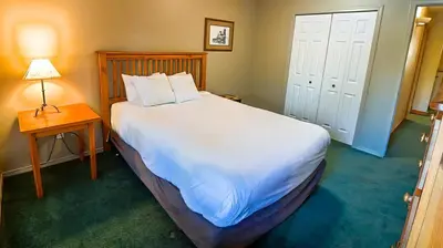 a bedroom with a large white bed with a table and a lamp at Polar Peak Chalet by Fernie Lodging Company in Fernie