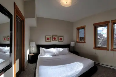 a bedroom with a large white bed and two windows at Mountain Escape sleeps 10 Guests in this 3BD 2BT Top Floor Condo with Mountain View in Canmore