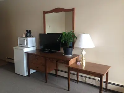 a room with a desk with a lamp and a mirror at Siesta Motel in Olds