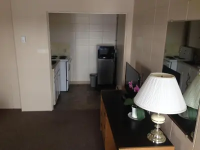 a room with a kitchen with a lamp on a desk at Siesta Motel in Olds