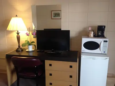 a kitchen with a desk with a microwave and a computer at Siesta Motel in Olds