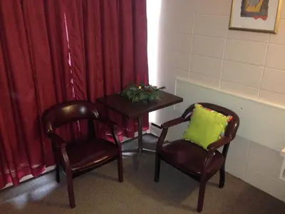 a room with two chairs and a table with a green pillow at Siesta Motel in Olds